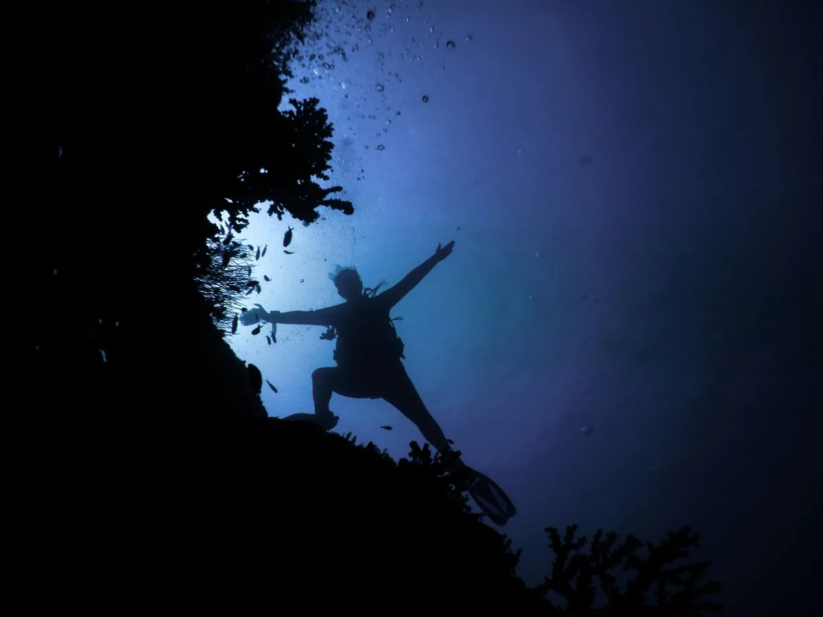 Scuba diver silhouetted against blue Maldives water